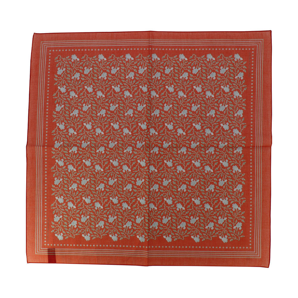 Pañuelo cuadrado estampado con flores verdes sobre fondo rojo.